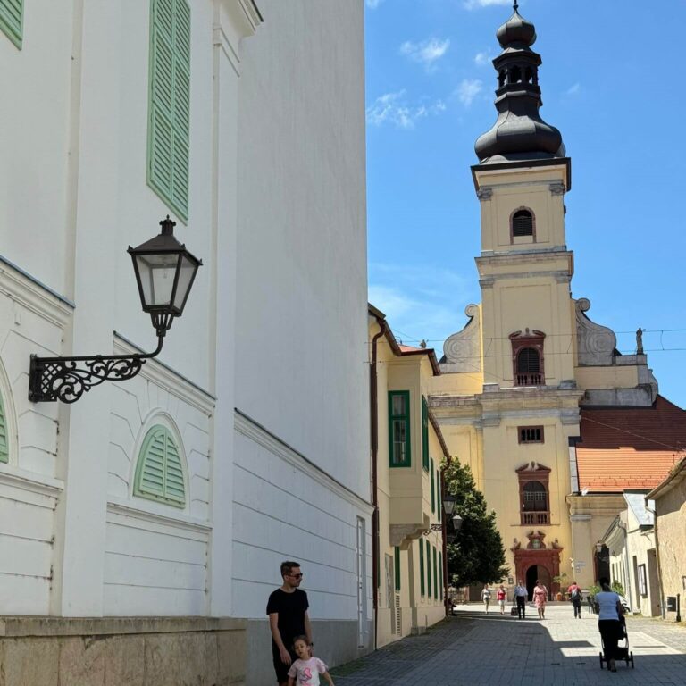 street of Trnava with church and lively vibrant street life during day trip to Trnava