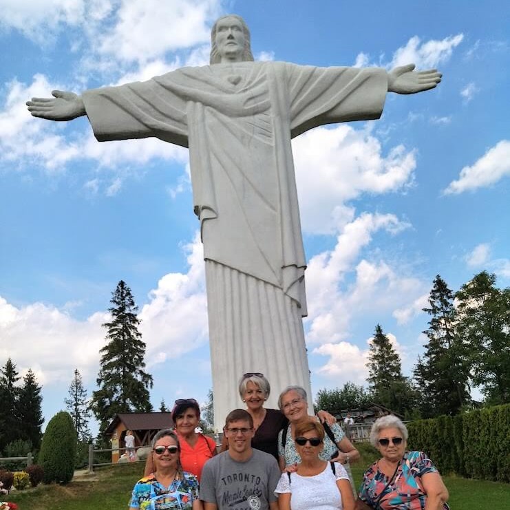 statue of Jesus in a small Orava village Klin. On the photo tour guide posing with the elderly clients from Spain